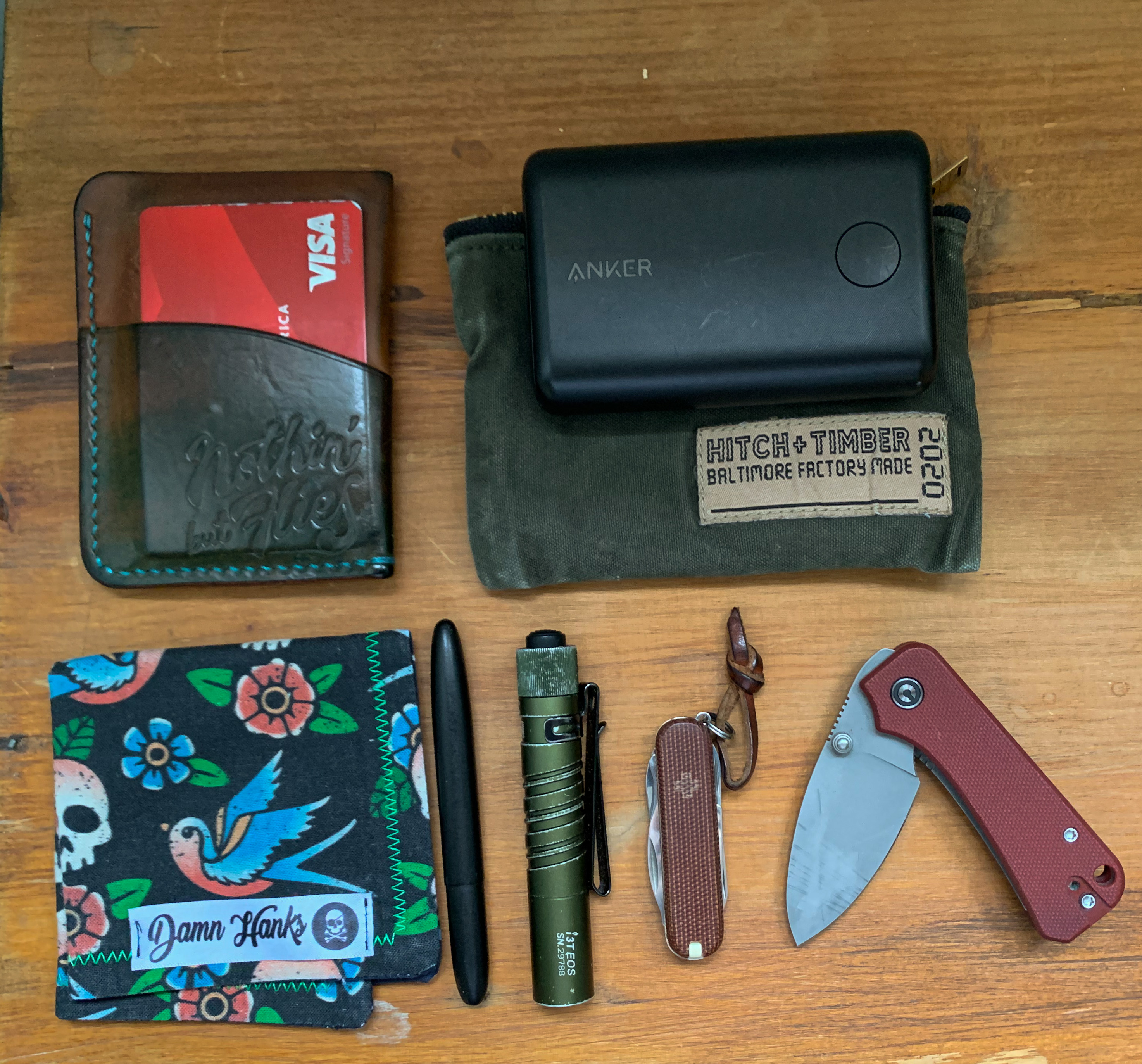 Picture of Chris’ gear including knife, multitool, pen, flashlight, backup battery, handkerchief, and wallet