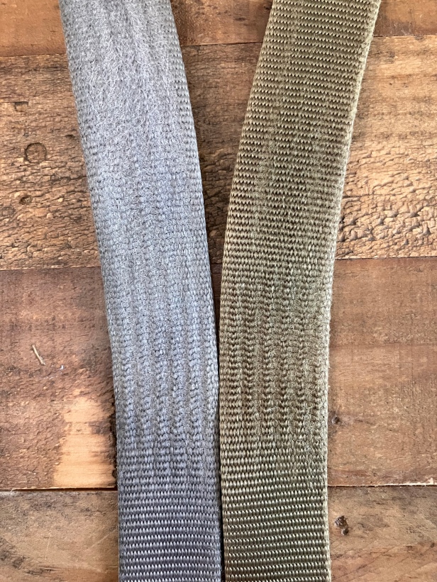 Two Patagonia Tech Web Belts in grey and olive green, with wear from the belt buckles