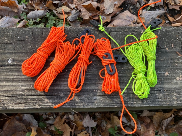 Guylines for tarp or tent with orange and yellow reflective cordage and plastic tensioners